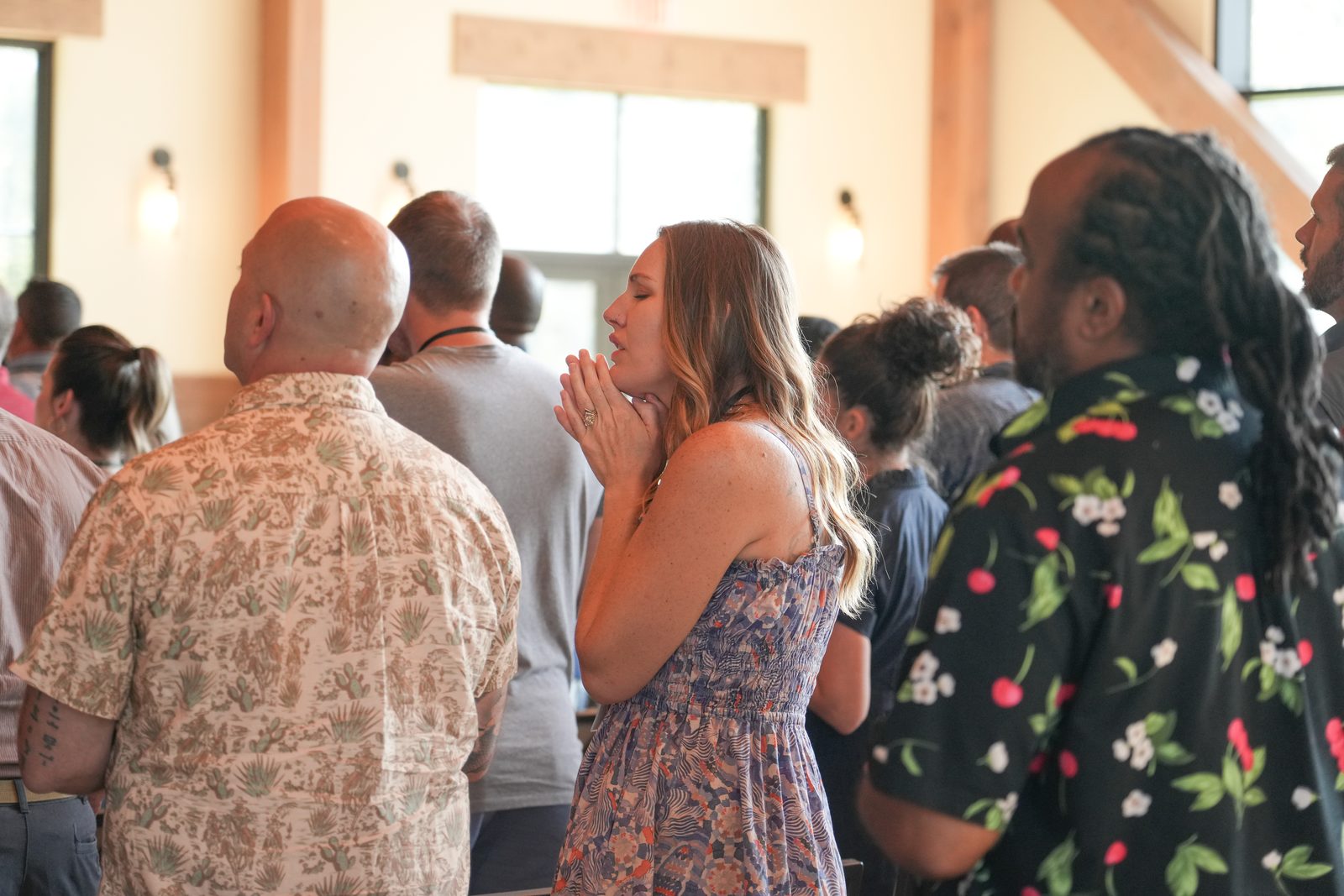 A woman praying with her hands clasped during worship, standing among the other couples in the session