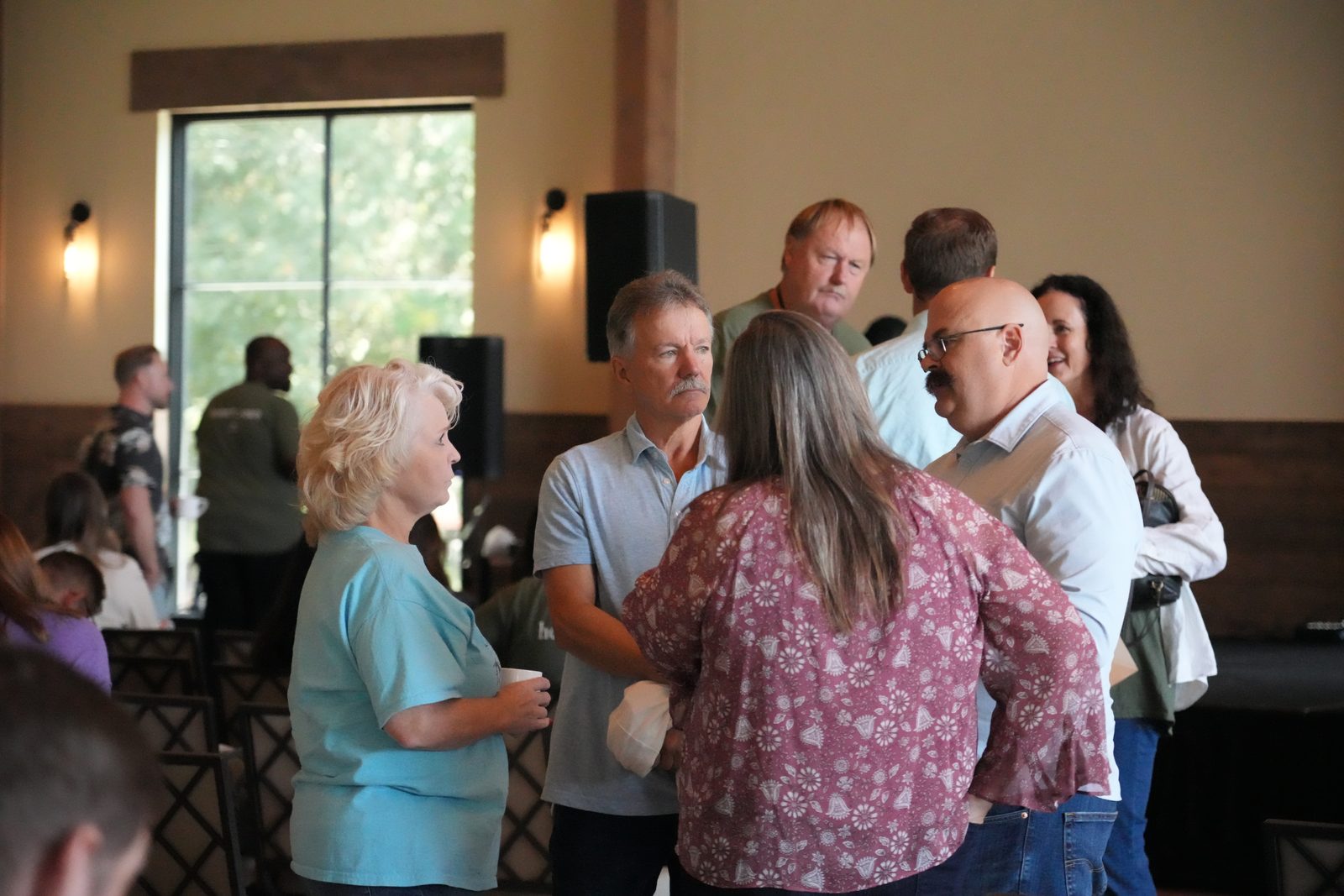 Couples talking in small groups between sessions, coffee cups in hand
